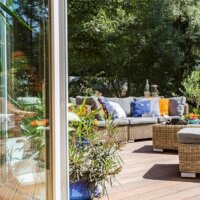 Sommerliche Terrasse mit Holzdielen und Möbeln aus Naturmaterialien